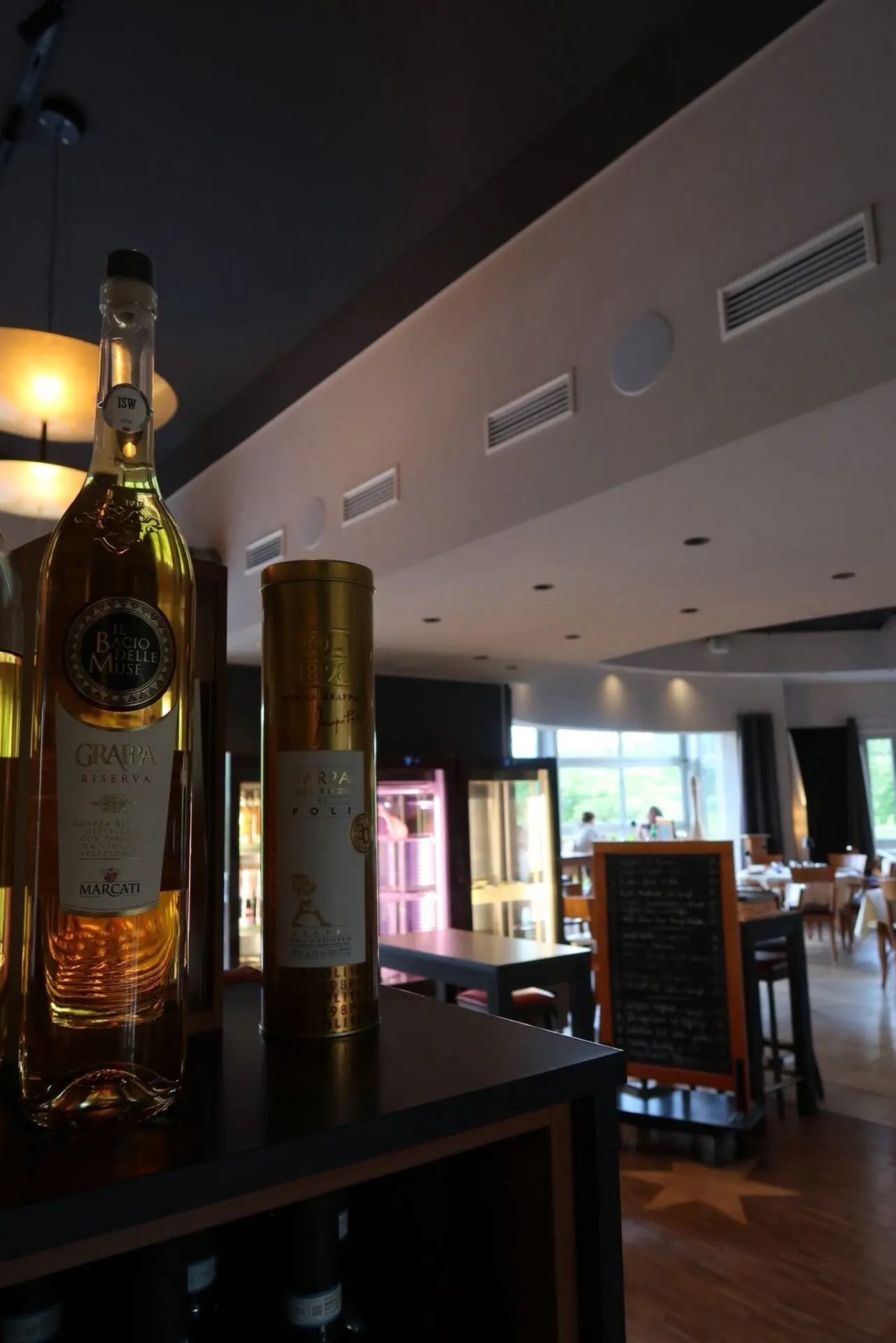 Eine Flasche Grappa mit goldener Farbe auf einem Regal in einem Restaurant.